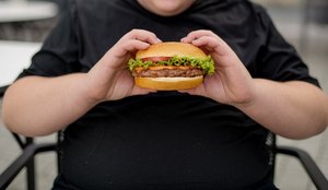 A photo of a young obese person holding a hamburge K6 MV Yhce Qg On GSB Hsfm Sw Q is L Zqc GS Qf2tf7 Sqz UEP Ew