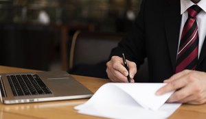 Homem no escritorio escrevendo no papel