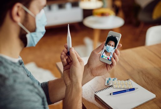 Closeup of man having online consultations with a doctor about his fever during coronavirus pandemic