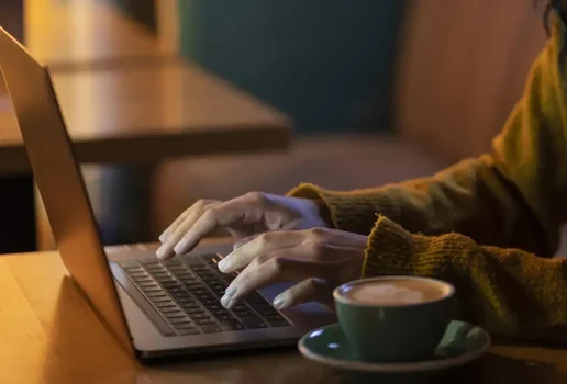 Mulher de lado trabalhando em seu laptop em uma cafeteria