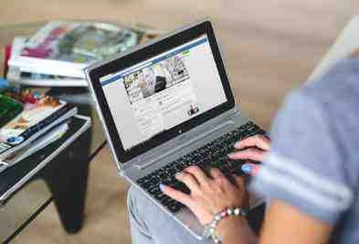 Woman working on laptop with magazines on stools