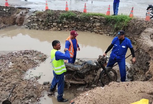 Operários retiram moto de bueiro durante obras de desobstrução na PB