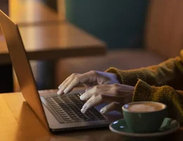 Mulher de lado trabalhando em seu laptop em uma cafeteria