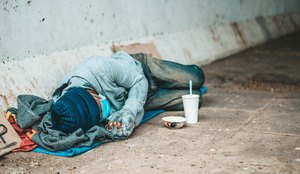 Mendigos deitados ao lado da rua com roupas sujas